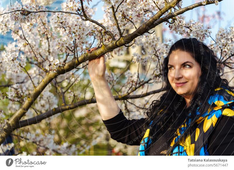 Young woman on the background of blooming cherry trees in the city park young spring urban blossom outdoors nature beauty springtime blossoms urban environment