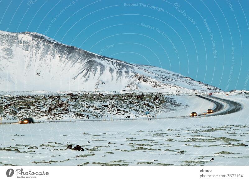 Road with moving cars and snowy rocky landscape in Iceland Winter Street Volcanic island Traffic infrastructure iced Motoring Road traffic StVO Blog Tourism