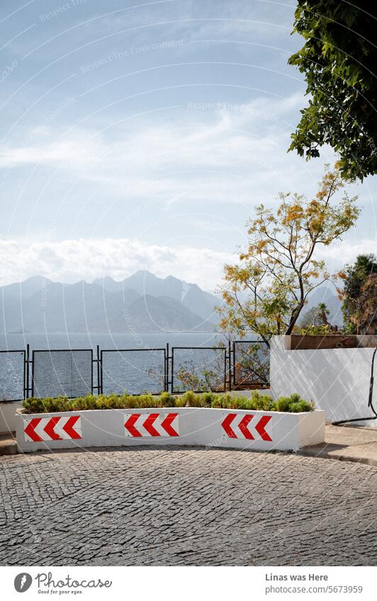 A picturesque road in Antalya, Turkey, with majestic mountains in the background and a calm sea. It's a perfect day for exploration, whether in the city or amidst the natural landscape.