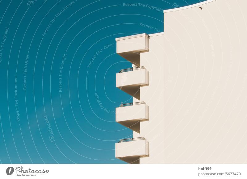 White exterior façade with balconies against a blue sky Minimalistic Balconies Blue sky Sky Apartment Building Free Symmetry Line Concrete High-rise facade