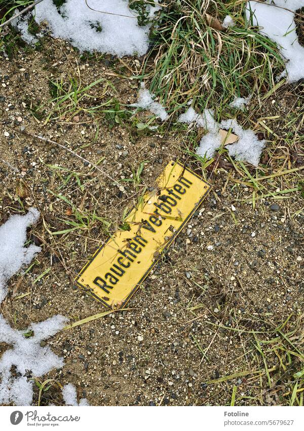 "No smoking" is written on the yellow sign lying on the cold, snow-covered ground. Signs and labeling Bans Signage Prohibition sign Warning sign Warning label