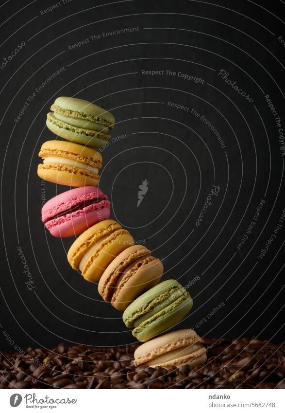 Stack of multi-colored macarons on a background of coffee beans, black background french macaroon meringue stack sweet almond bakery nobody nutrition pastry