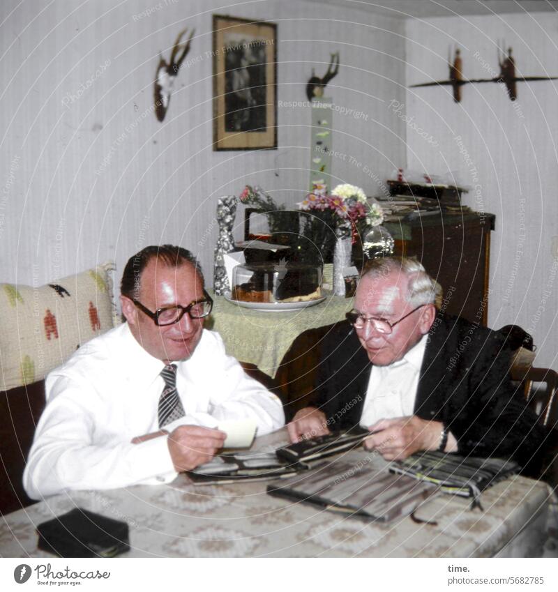 Days of remembrance Man Image viewing men Former then Photo album 2 living room Living or residing Living room Sofa Table stag's antlers Shirt Tie Smiling