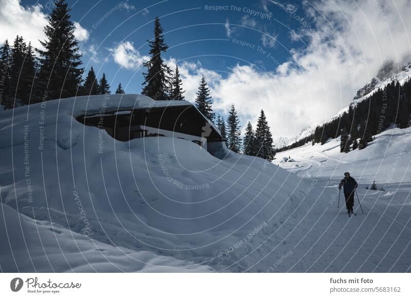 Snow-covered hut in the mountains. Cross-country skiers in the ski area Hut Alps Skier cross-country skiing Winter sports Log home Mountain Winter vacation