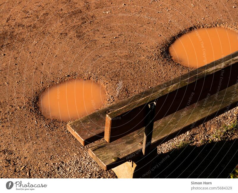 Puddles in front of a park bench Park bench Earth off rest Rain Water Wet after the rain Weather signs of the times Lanes & trails Repeating Subsoil