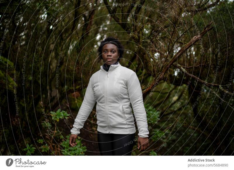 Black woman walking along path in forest tourist calm tree park alone countryside female young casual african american ethnic black serious green environment