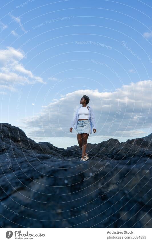 Black woman traveler standing on rocky cliff lake landscape mountain water nature female young african american ethnic black curly hair casual tourist volcanic