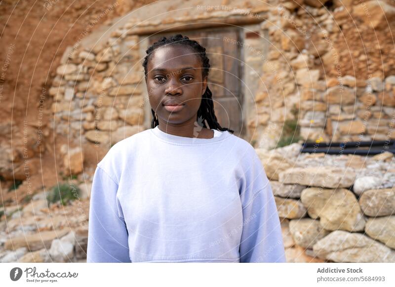 Confident black woman in front of rustic stone backdrop portrait confidence stone wall african american wooden door sweater casual natural outdoor daytime