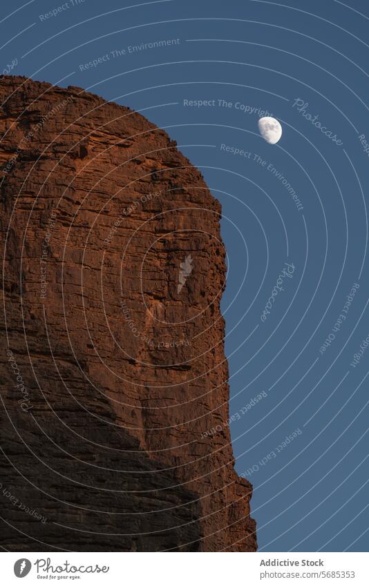 Desert cliff with moon at dusk desert serene nature landscape rock sky evening waxing gibbous towering outdoor peaceful tranquil Guelta Essendilene beauty