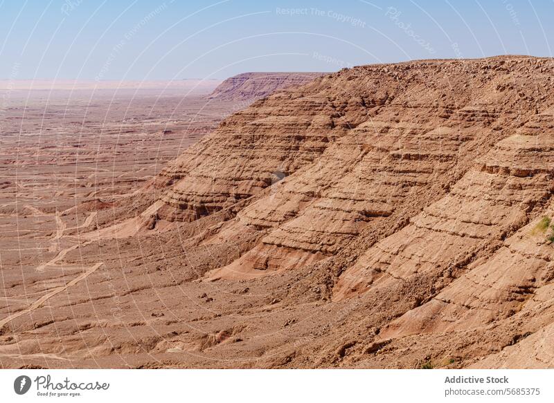 Vast desert landscape of Plateau de Fandoun under a clear sky arid terrain rock formation strata blue vast wilderness nature outdoors geological erosion