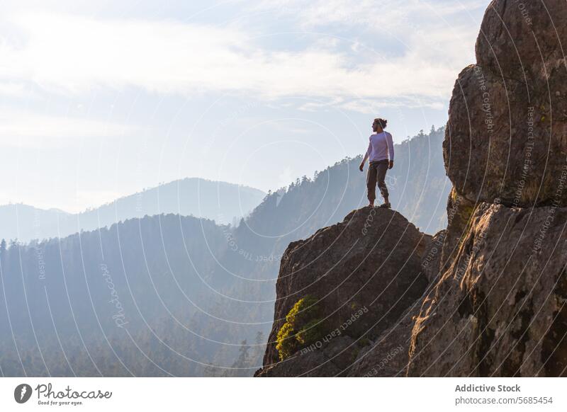 Brunet man standing on rocky cliff in highlands tourist admire mountain sneakers scenery pants traveler nature vacation tourism majestic landscape adventure