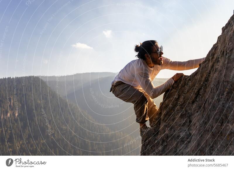 Brave young man climbing mountain cliff ridge positive brave sunglasses style cloth nature adventure highland travel male smile cheerful rough range happy