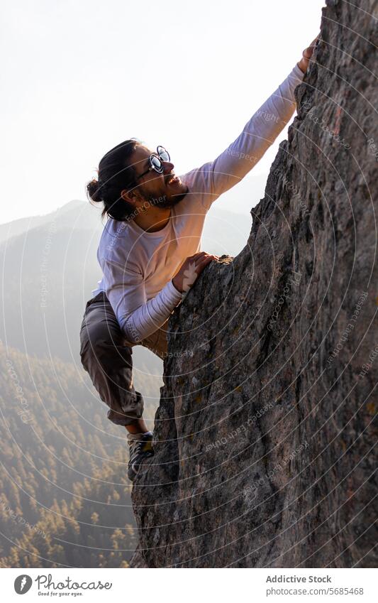 Brave young man climbing mountain cliff ridge positive brave sunglasses style cloth nature adventure highland travel male smile cheerful rough range happy