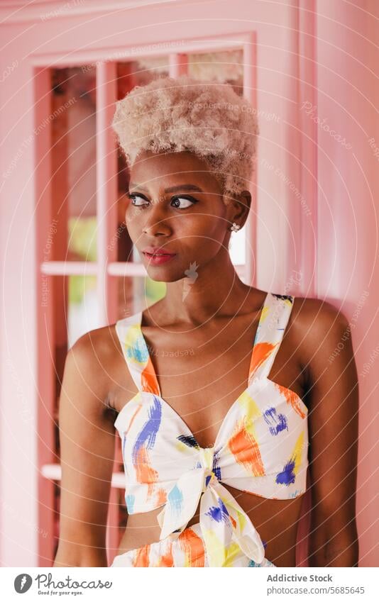 Stylish black woman in summer outfit besides pink wall style afro appearance young cheerful makeup smile trendy happy feminine african american portrait