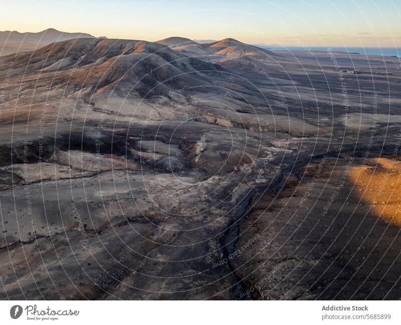 Golden hour light casts shadows over the ancient volcanic landscape along Fuerteventura's north coast, near El Cotillo and Majanicho, by Faro del Toston