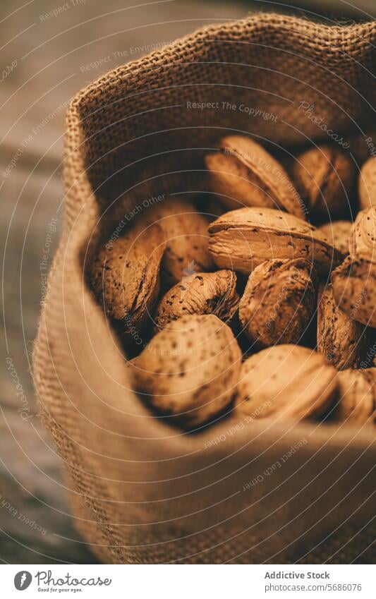 Burlap Sack of Almonds on Wooden Surface almond burlap sack wooden rustic fresh nut shell texture harvest organic natural brown close-up food ingredient