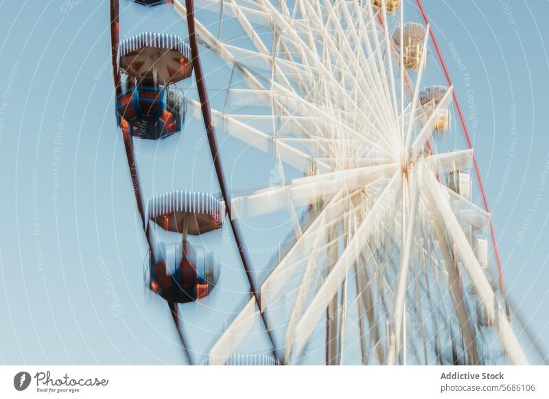 From below dynamic, motion-blurred Ferris wheel with a sense of speed and movement under a bright blue sky amusement park ride fairground leisure outdoor