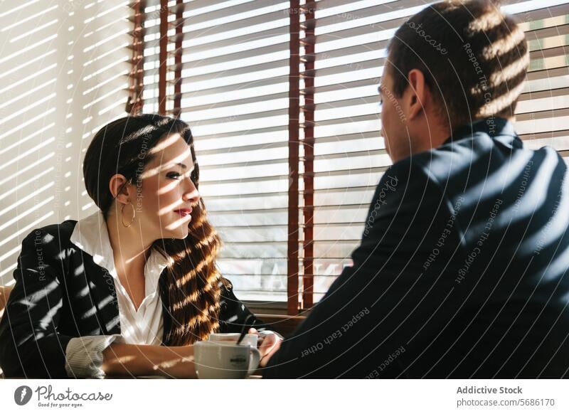 Business meeting in sunlit Madrid cafe business professional conversation madrid spain window blinds table man woman morning coffee sunlight shadow dialogue