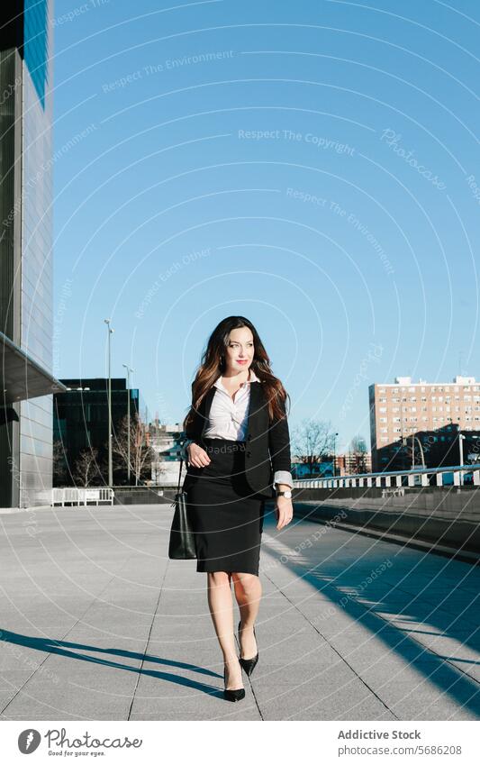 Confident businesswoman walking in Madrid professional madrid spain urban confident business attire city modern sidewalk skyscraper sunny executive career style