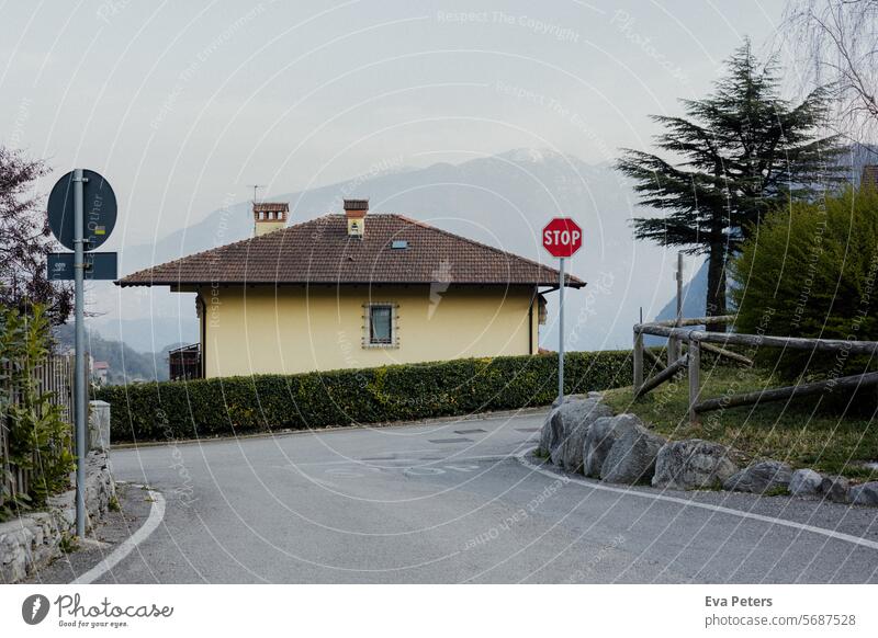 Yellow house on a road on a hillside with mountains in the background Looking Tenno Trentino Tourism vacation trento Mountain Italy Summer Landscape Nature Blue