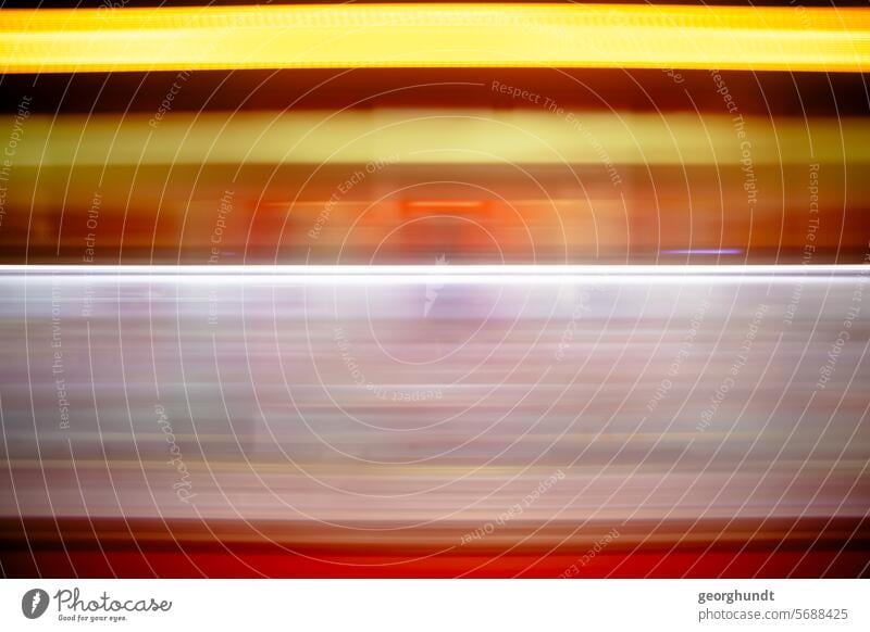 Blurred contours of a passing red train with yellow display and window. Behind it details of a train station. Track drive past hazy In transit Red Train station