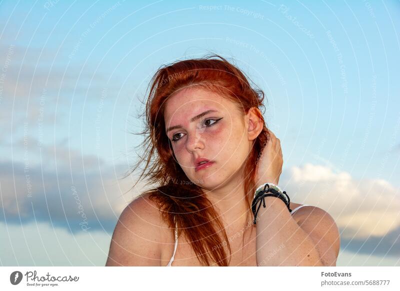 Young woman with windblown hair and sky portrait Active cute dress European young windy Freckles female attractive summer girl sandy beach face outside