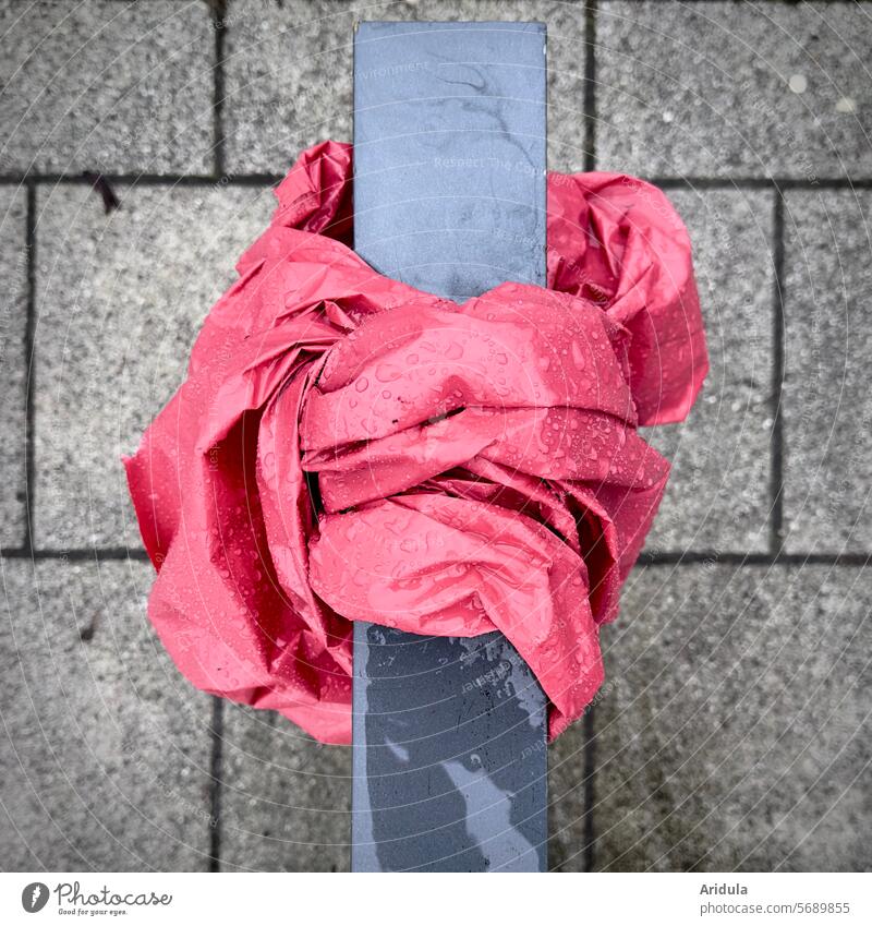 Pink plastic with raindrops tied around bike stand Plastic pink Rain Rain pots bizarre Stone slab Trash Recycling packaging waste Structures and shapes