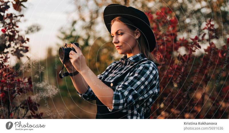 Young pretty woman takes pictures with DSLR camera outdoors on autumn background active adult art attractive beautiful beauty caucasian cheerful concept