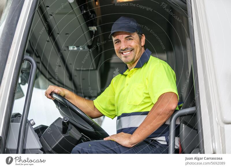 Cheerful male driver sitting in truck while looking at camera man smile positive uniform happy vehicle auto glad cap cheerful optimist t shirt friendly casual