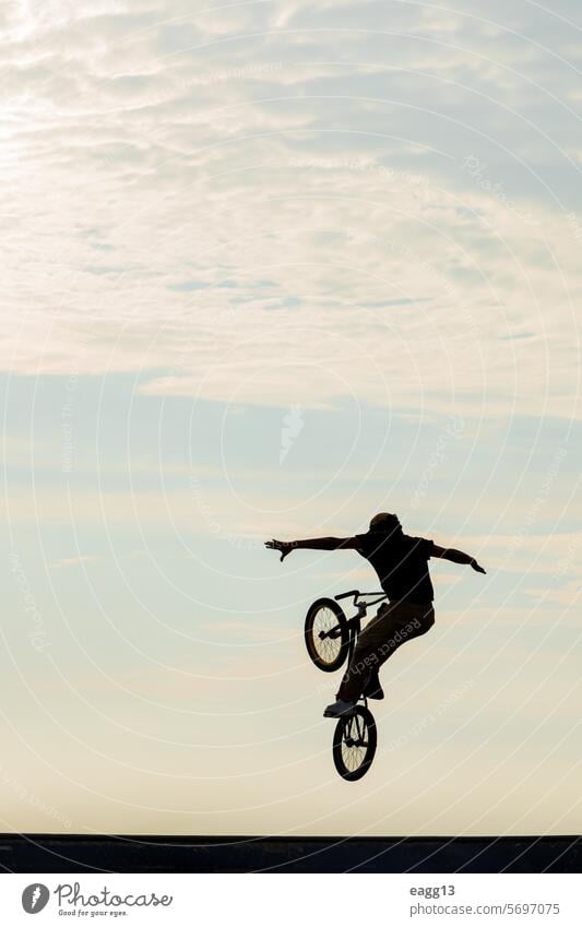 Freestyle cyclist practicing street BMX acrobat adrenaline athlete balance bicycle bmx cloudscape cycling danger determination dramatic sky dusk effort