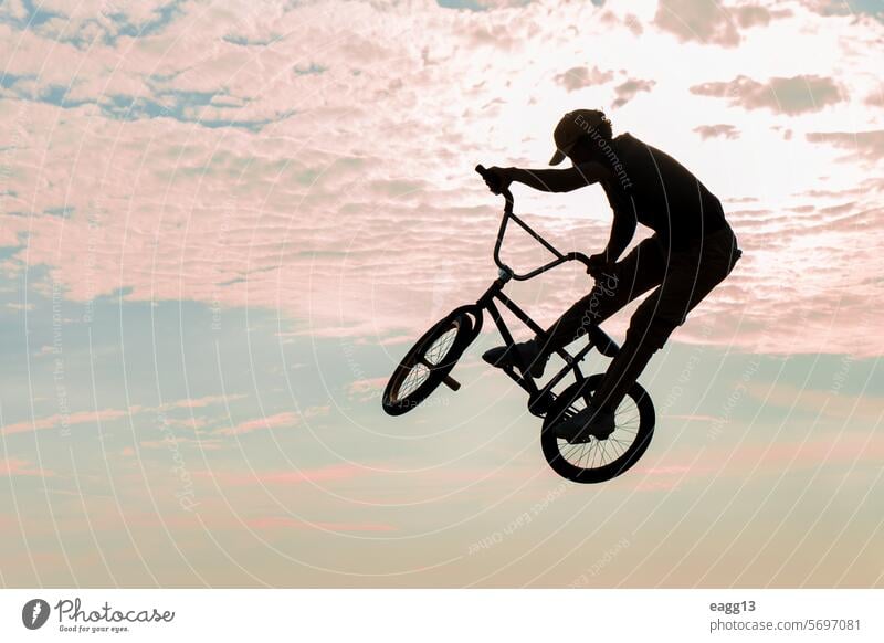 Freestyle cyclist practicing street BMX acrobat adrenaline athlete balance bicycle bmx cloudscape cycling danger determination dramatic sky dusk effort