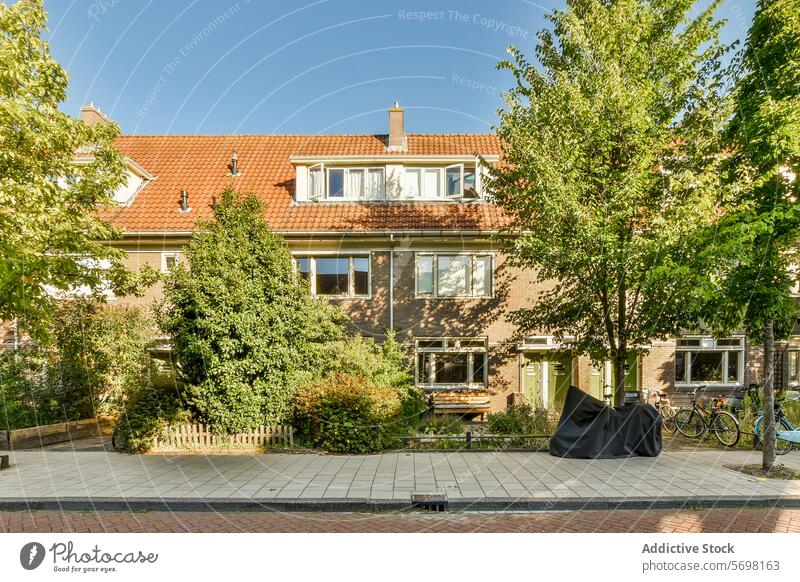 Suburban house with garden and bicycles parked outside suburban sunny residential brick roof tiled peaceful front charming tree sidewalk greenery outdoor