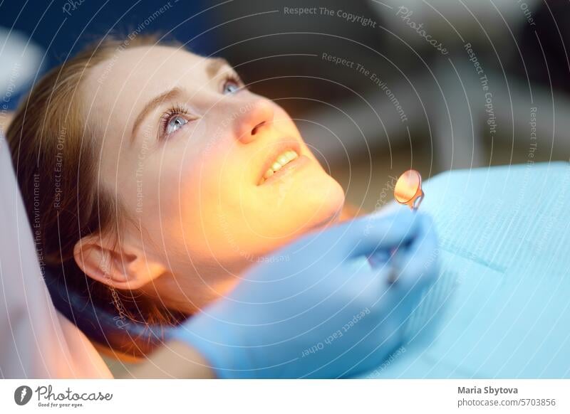 Dentist and patient at modern medical center. Doctor treats a young woman teeth in hospital. Practitioner examines the patient before orthodontists or prosthetics treatment.