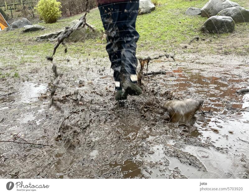 Child with rain pants jumps in a muddy puddle Puddle rainy rainy weather Autumn Autumnal autumn atmosphere roller coaster ride Rain Weather Gray rainy day