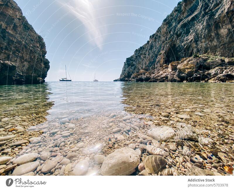 Serene Beach Cove with Sailboats and Clear Waters beach cove sailboat clear water pebble cliff horizon tranquil serene bright sky crystal-clear seascape