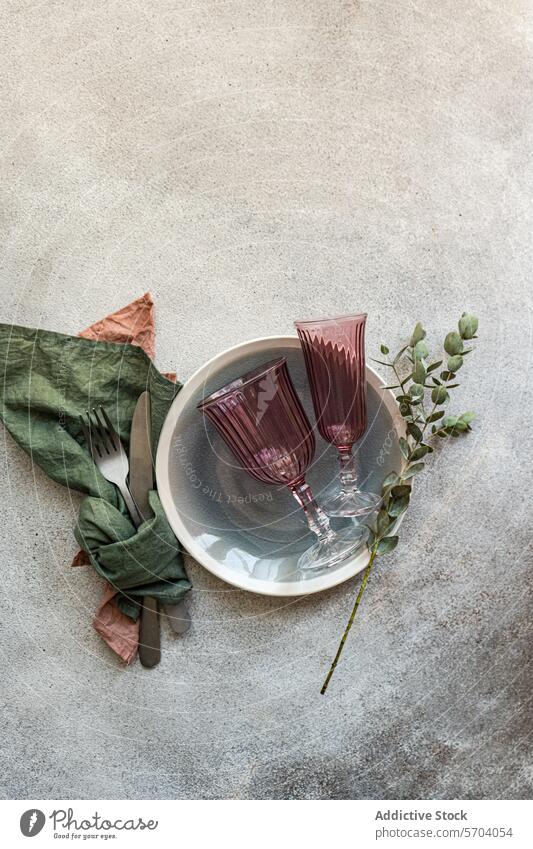 Elegant table setting with burgundy glasses and greenery wine silver bowl texture surface elegant sophisticated decor dining arrangement style concrete