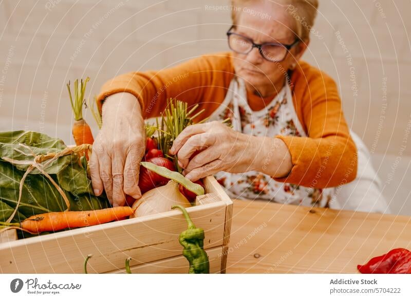 Senior hands sorting fresh vegetables into wooden crate senior harvest organizing tabletop elderly person variety harvested box carrot onion leaf green