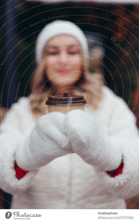 Woman in white wool mittens and fur coat holding take away coffee cup outdoors, soft focus on hands woman winter close-up fashion hat blonde holiday pine fir