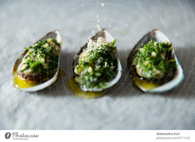 Prepared for cooking dinner ingredients - fresh opened green mussels with butter, greens and seasonings on baking sheet. Kitchen counter appetizer background