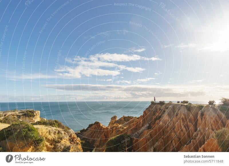 Tourist standing on golden rock cliffs at the coastline of the Atlantic Ocean with near the Cave of Benagil, Algarve, Portugal travel portugal sea beach algarve