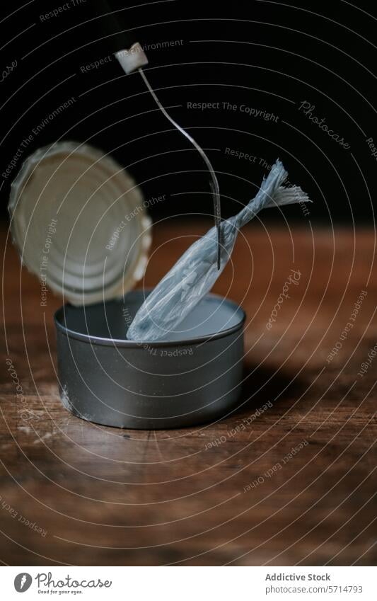 An artistic still life setup with a plastic bag creatively placed on a fork over an open tin can, symbolizing the intersection of food consumption and plastic waste