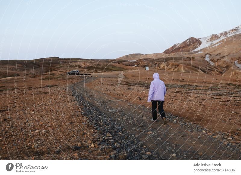 Woman exploring the desolate terrains of Iceland iceland travel adventure woman female landscape barren hill gravel path pink jacket walking explore off-road