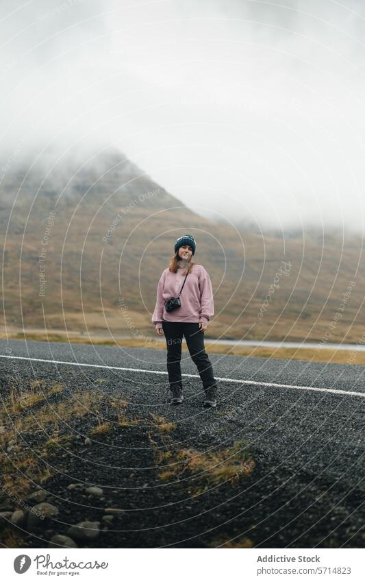 Female traveler on a foggy Icelandic road iceland woman female mountain mist landscape adventure solo journey nature outdoor deserted remote tranquil serene