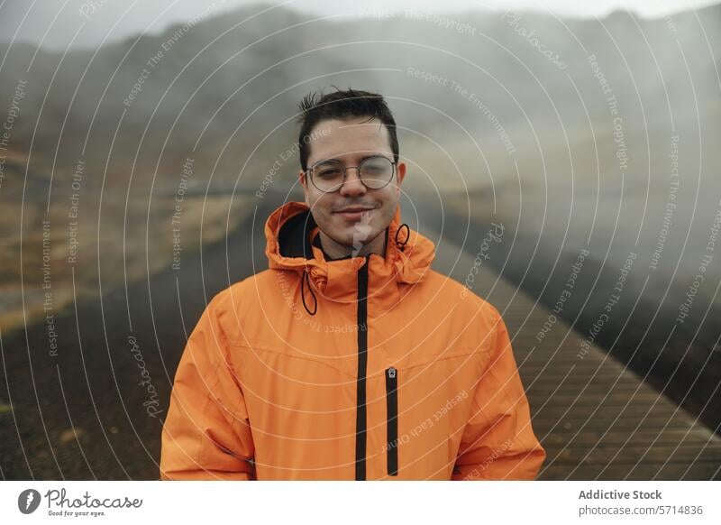 Man in Orange Jacket Enjoying Misty Iceland Landscape iceland travel adventure man male outdoor mist landscape orange jacket smile glasses fog boardwalk nature