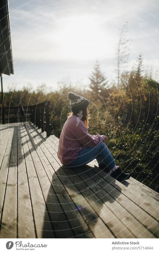 Serene moment on sunny wooden deck in Iceland iceland trip woman female serene peaceful sitting trees outdoors nature calm leisure travel sunlight relaxation