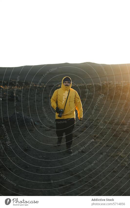 Man in Yellow Jacket Exploring Icelandic Terrain iceland man explorer volcanic landscape sunset photographer yellow jacket camera male travel adventure nature