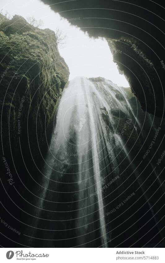 Majestic waterfall plunging from rocky cliffs in Iceland iceland cascade nature travel moss flow stream sunlight soft light mist spray natural landscape