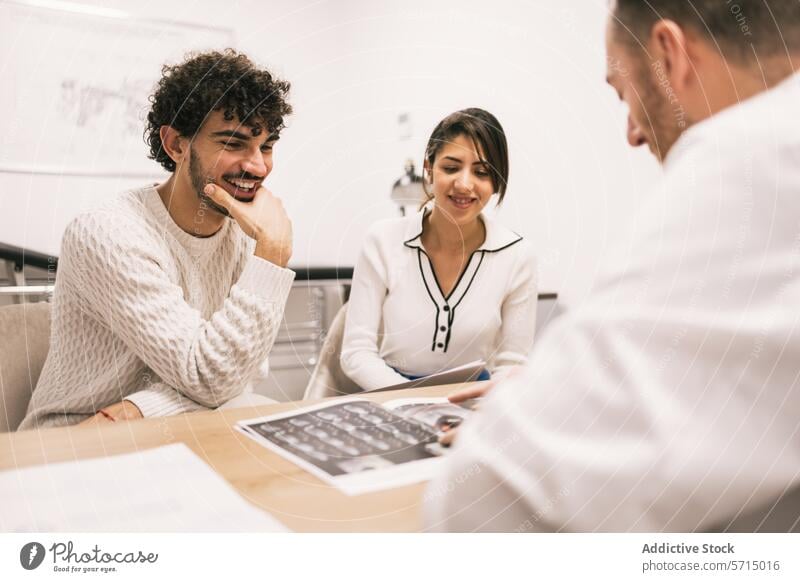 Smiling doctor discusses X-rays with patients at clinic x-ray medical office healthcare health care consultation communication couple male female smiling