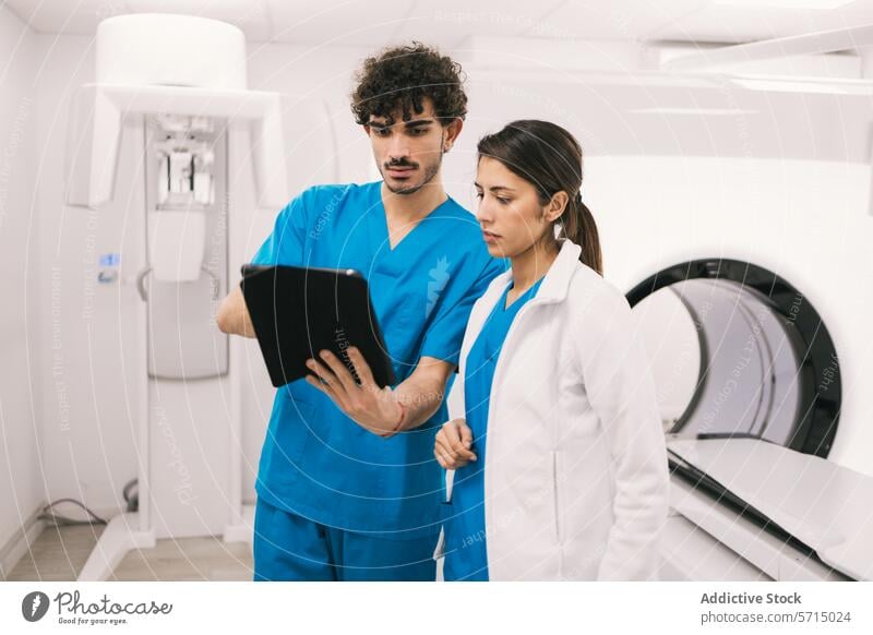 Medical professionals discussing patient's records in hospital healthcare male female tablet digital medical doctor nurse scrubs lab coat mri equipment worker