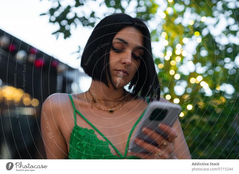 Modern Urban Woman Using Smartphone in Madrid at Dusk woman smartphone madrid urban dusk four towers bokeh lights evening fashion style dress green young adult